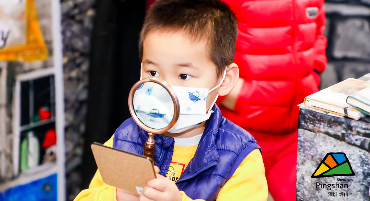 A kid uses a magnifying glass to examine a product at the exhibition Dec. 5.