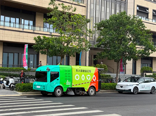 A driverless AI sanitation vehicle and a robotaxi operate on a street in Pingshan.